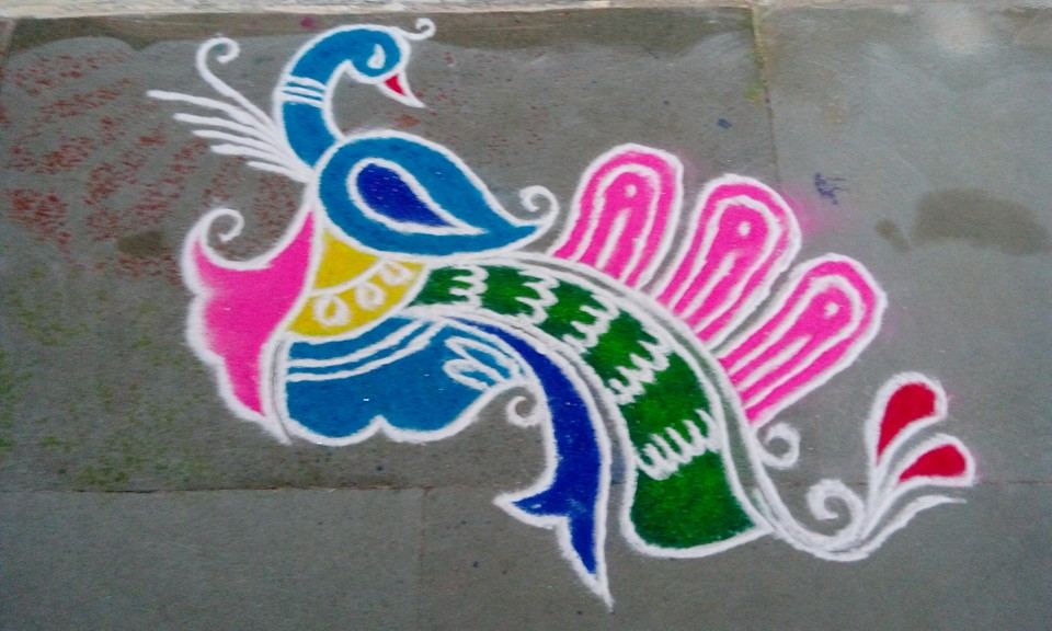 Green and magenta rangoli with a lit diya at centre